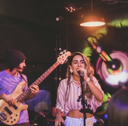 a-woman-singing-into-a-microphone-while-holding-a-guitar.jpg a woman singing into a microphone while holding a guitar